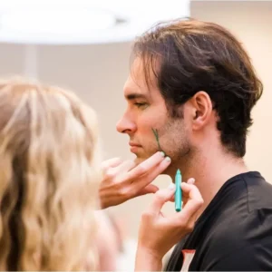 A woman marking a man with a green marker planning the injection sites prior to Botox treatment.