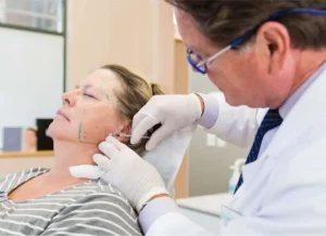A dentist injecting a patient therapeutically in the jaw/masseter region with Botox.